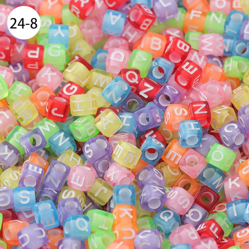May include: A close-up of a large pile of colorful alphabet letter beads. The beads are made of translucent plastic and have white letters on them. The beads are in a variety of colors, including red, orange, yellow, green, blue, purple, and pink.