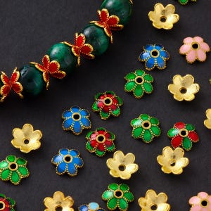 May include: Assortment of colourful flower-shaped metal bead caps in various colours, including red, green, blue, gold, and pink. The caps are designed to be used for jewellery making and crafting.