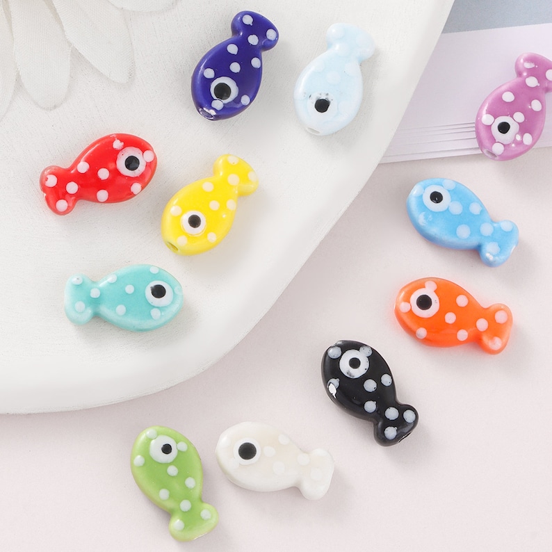 Pode incluir: Conjunto de contas de peixe de vidro coloridas com bolinhas brancas e um &uacute;nico olho preto. As contas medem aproximadamente 2,5 cm de comprimento e s&atilde;o perfeitas para fazer joias ou artesanato.