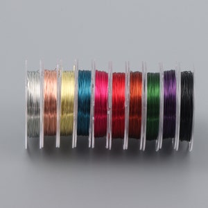 May include: A set of ten spools of colorful wire, each spool is in a clear plastic container. The colors of the wire are silver, copper, gold, teal, pink, red, brown, green, purple, and black.