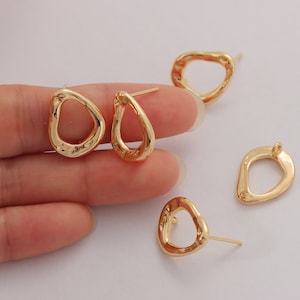 May include: Four gold-toned earrings with irregular oval shapes and a small hole in the center. The earrings have a post backing.
