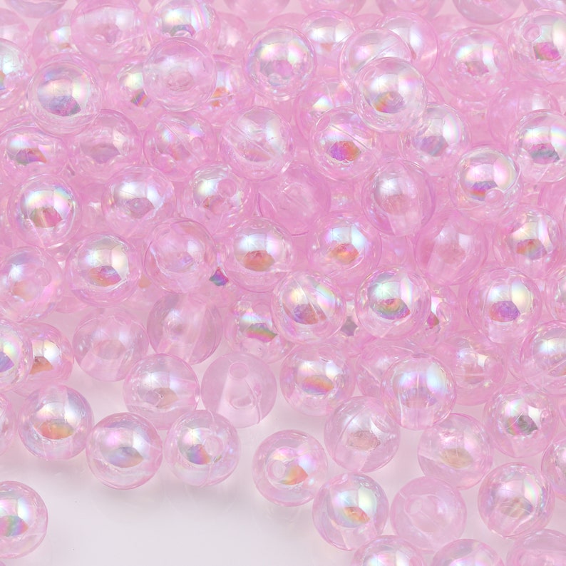 May include: A large pile of iridescent pink plastic beads. The beads are round and have a smooth, glossy finish.