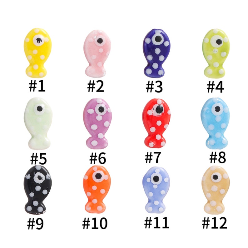 Pode incluir: Doze pingentes de peixe de cer&acirc;mica com corpos de diferentes cores e bolinhas brancas. Cada peixe tem um olho preto e um c&iacute;rculo branco no centro do olho. Os peixes s&atilde;o numerados de 1 a 12.