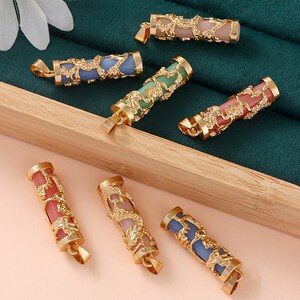 May include: Six gold-tone pendants with a dragon design. Each pendant features a different colored stone: pink, green, blue, light blue, and two shades of pink.