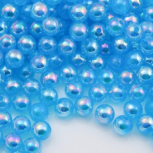 May include: A large pile of iridescent blue plastic beads. The beads are round and have a smooth, shiny finish.