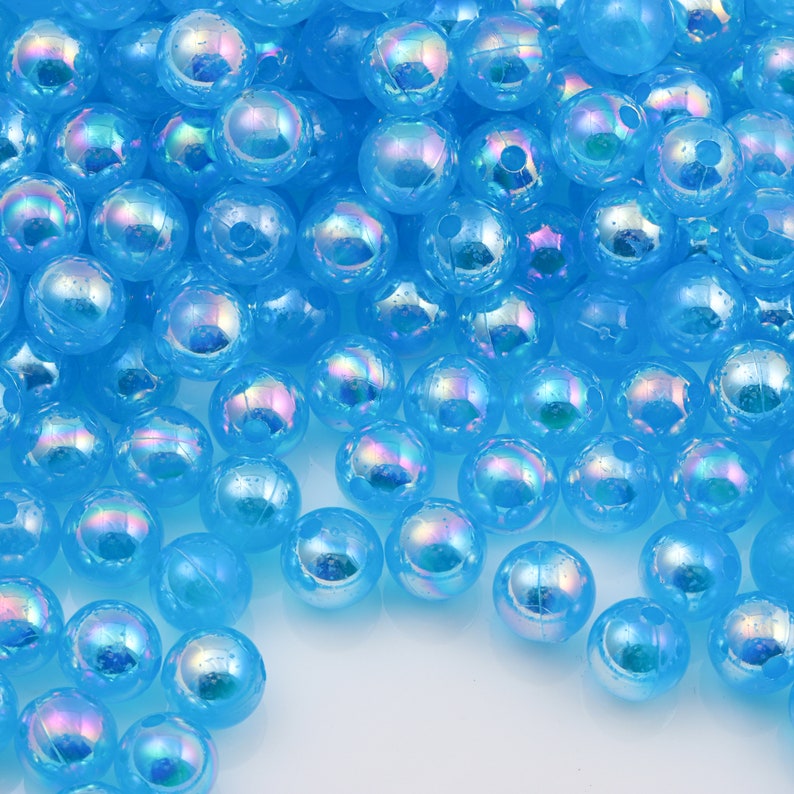 May include: A large pile of iridescent blue plastic beads. The beads are round and have a smooth, shiny finish.