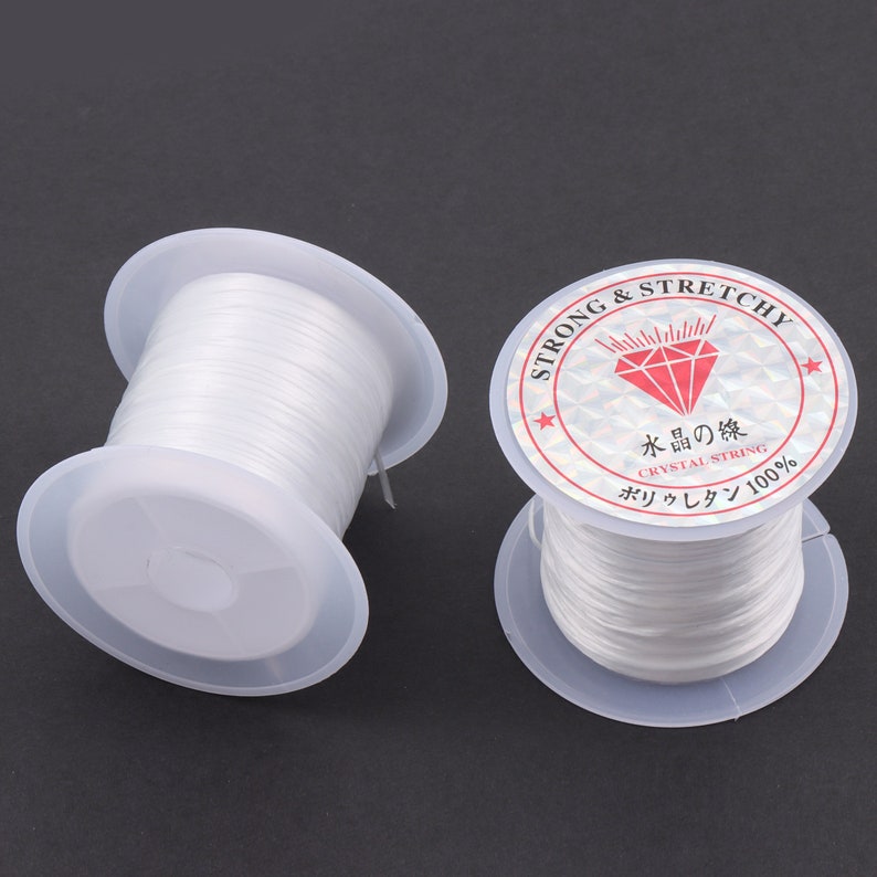 Puede incluir: Dos carretes de hilo el&aacute;stico blanco, etiquetados como "Strong & Stretchy" y "Crystal String 100%".