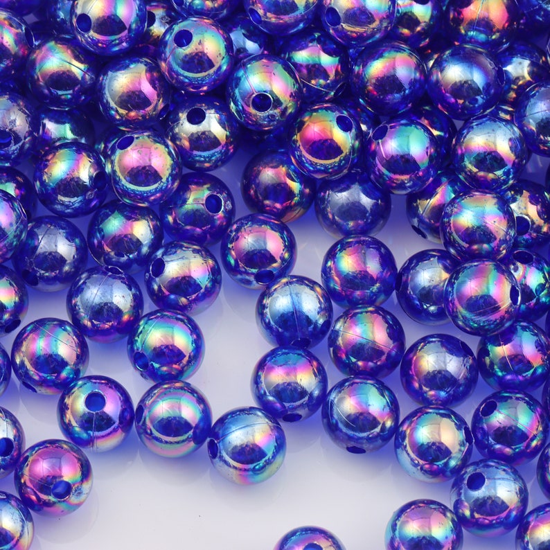 May include: A large pile of iridescent blue round beads. The beads have a shiny, reflective surface.