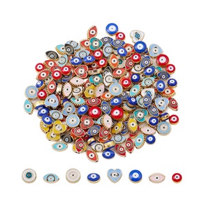 Può includere: Un grande mucchio di perline colorate di occhio turco in varie forme, tra cui ovale, a forma di cuore e rotonda. Le perline sono in metallo e hanno una finitura dorata. Le perline sono decorate con smalto blu, rosso, bianco e giallo.