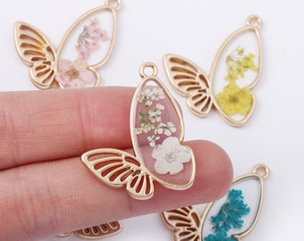 May include: Gold-colored butterfly-shaped pendants with dried flowers encased in clear resin. The wings are openwork, and the flowers are pink, yellow, and blue. Each pendant has a small loop for hanging.