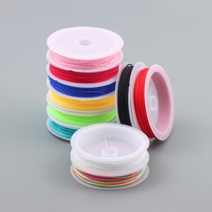 May include: A set of colourful spools of thread, each wound around a white plastic bobbin. The spools are stacked in a tower, with the top spool being pink, followed by red, blue, yellow, green, and turquoise. The bottom spool is a rainbow of colours.