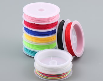 May include: A set of colorful spools of thread, each wound around a white plastic bobbin. The spools are stacked in a tower, with the top spool being pink, followed by red, blue, yellow, green, and turquoise. The bottom spool is a rainbow of colors.