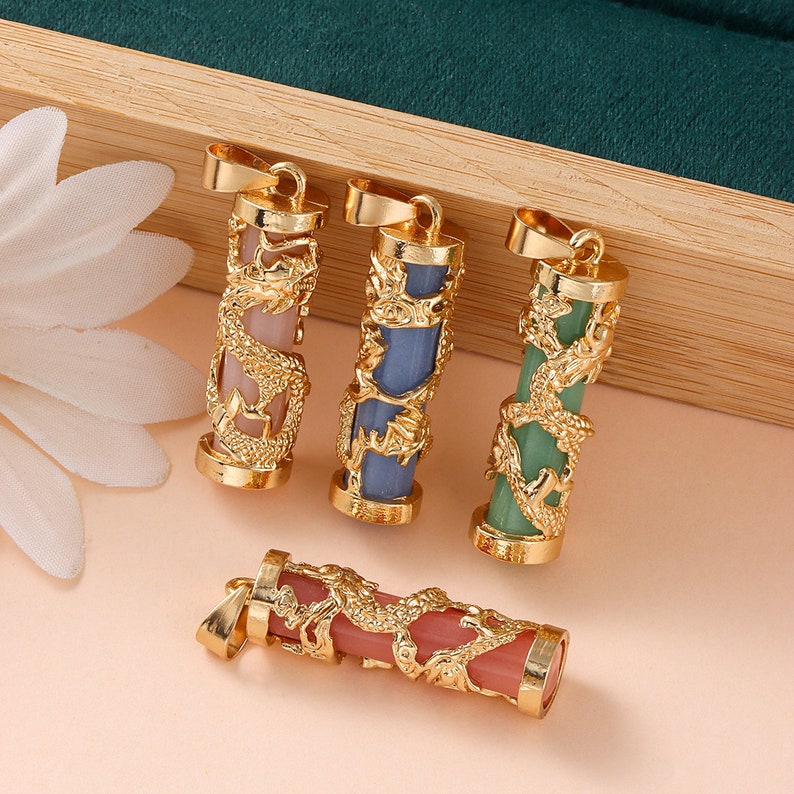 May include: Four gold dragon pendant charms with different colored stones inside. The stones are pink, blue, green, and pink. The charms are all about 2 inches long.