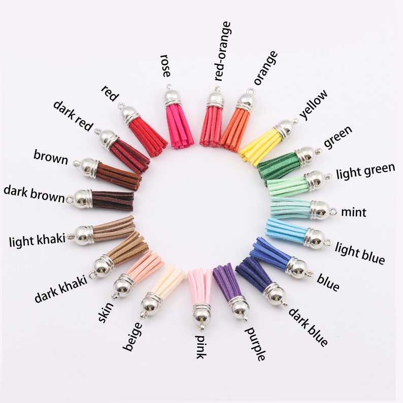 May include: A set of 18 colourful suede tassels with silver metal rings. The tassels are arranged in a circle, with the colours ranging from dark red to light blue.