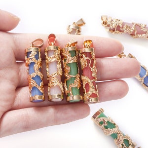 May include: Five gold dragon pendants with different colored stones. The stones are blue, pink, green, and red. The pendants are all in the shape of a cylinder with a dragon design.