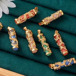 May include: Seven gold dragon pendant necklaces with different colored stones. The stones are pink, green, blue, and red. The pendants are all in the shape of a cylinder with a dragon design.