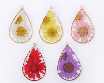 May include: Five teardrop-shaped pendants with dried flowers encased in clear resin. The pendants feature gold or copper-colored metal frames and include white, yellow, pink, red, and purple flowers. Each pendant has a small loop at the top for hanging.