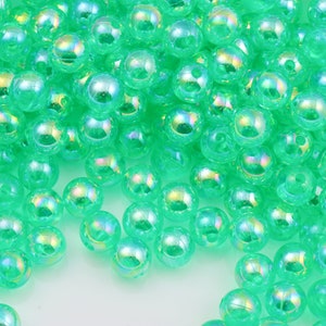 May include: A large pile of iridescent green plastic beads. The beads are round and have a smooth, shiny finish.