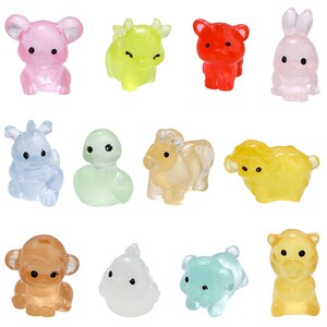 May include: A collection of twelve translucent animal figurines in various colors. The figurines include a pink mouse, a yellow cow, a red bear, a pink rabbit, a blue dragon, a green snake, a tan horse, a yellow sheep, a brown monkey, a white bird, a blue bear, and a yellow tiger.