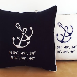 May include: Two decorative throw pillows with anchor designs. One pillow is black with a white anchor and coordinates, the other is white with a blue anchor and coordinates.