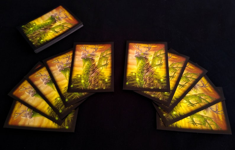 May include: A set of 10 cards featuring a green, deer-like creature with antlers, standing in a forest setting with a sunset background. The creature is surrounded by glowing green lights.