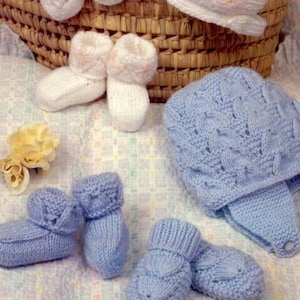May include: A set of knitted baby clothes in white and blue. The set includes a white hat, white booties, blue booties, and a blue hat.
