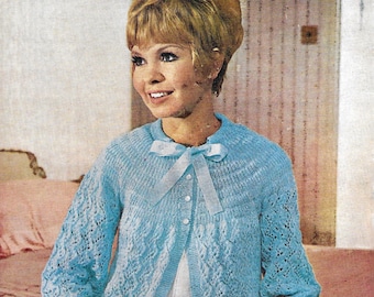 May include: A light blue knitted cardigan with a white ribbon tied at the neckline. The cardigan has a lace pattern and is buttoned up the front. The model is wearing a white blouse underneath. The pattern number is 855. The text on the image reads "Wendy 3 PLYS... 40/44" BUST from 9 BALLS"