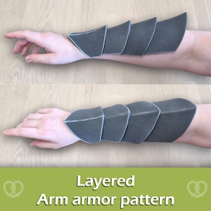 May include: A set of dark grey, layered arm armour pieces featuring a segmented design with four overlapping plates. The armour is worn on the forearm, extending from the wrist towards the elbow. The text Layered Arm armour pattern is visible.