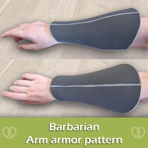 May include: A dark grey forearm guard with light grey piping along the seams, worn on the lower arm. The text "Barbarian Arm armour pattern" is displayed in white letters on a green background at the bottom of the image.
