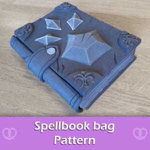 May include: A dark gray spellbook bag pattern with a strap closure. The bag features raised geometric shapes and decorative corner accents. The text "Spellbook bag Pattern" is displayed on a purple background.