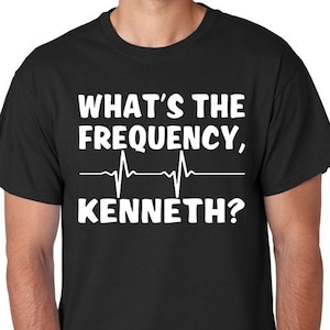 May include: Black t-shirt with white text that reads "What's the frequency, Kenneth?" with a stylized EKG line underneath.