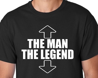 May include: Black t-shirt with white text that reads "The Man The Legend" with an arrow pointing up above the text and an arrow pointing down below the text.