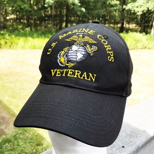 May include: Black baseball cap with a yellow embroidered US Marine Corps logo and the word "Veteran" underneath.