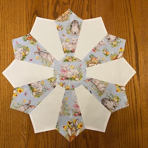 May include: A white and blue table runner with a starburst design. The runner features a variety of spring-themed animals, including bunnies, lambs, and a dog. The runner is perfect for adding a touch of spring to your home decor.
