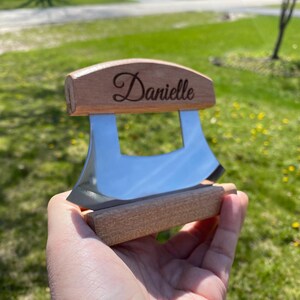 May include: A personalized wooden cheese knife with a stainless steel blade. The handle is engraved with the name "Danielle".