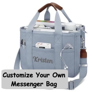 May include: A light blue messenger bag with brown leather handle accents, featuring the name Kristen printed on the front pocket. The bag includes multiple exterior pockets holding pens, a power bank, and wired earbuds, with a detachable shoulder strap.