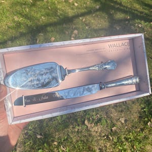 May include: A silver dessert serving set, including a cake server and knife, presented in a decorative box. The server and knife are engraved with the names "Ian & Julia" and the date "November 23, 2024". The box is labeled "Wallace Entertaining".
