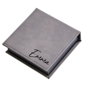 May include: A gray faux leather box with the name "Emma" engraved on the top.