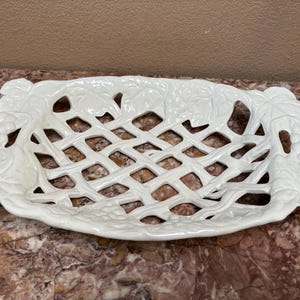May include: A white ceramic serving dish with a lattice design. The dish is rectangular with grape and leaf accents around the edges. The dish is approximately 14 inches long and 8 inches wide.