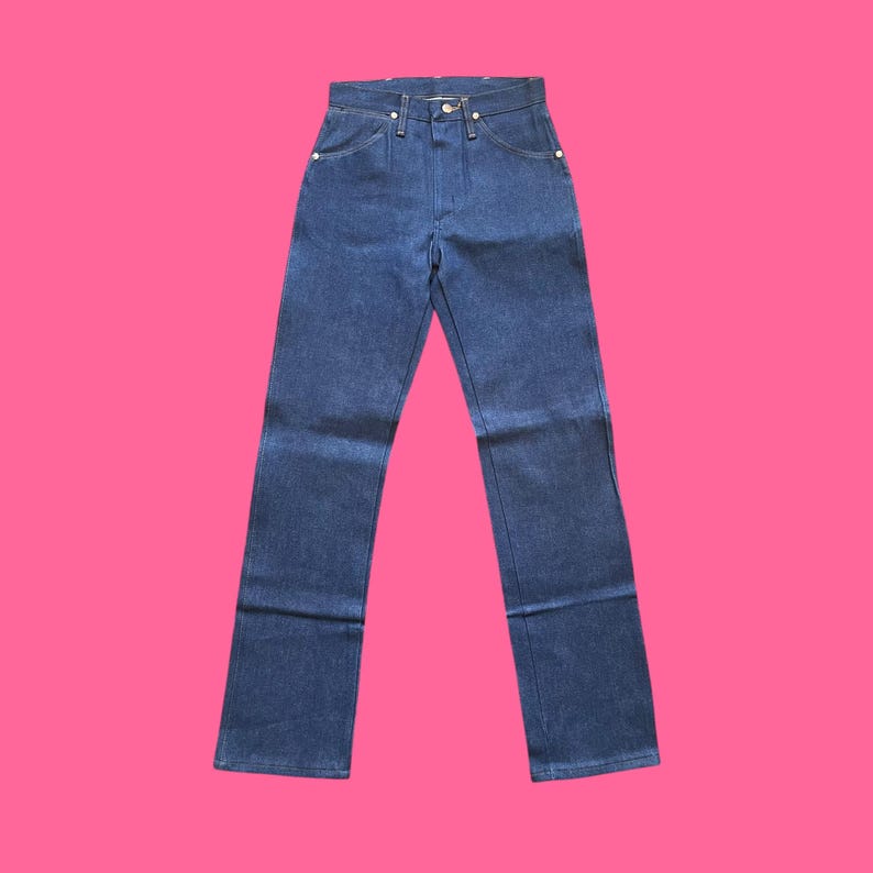 Op de afbeelding: Donkerblauwe denim jeans met een klassiek ontwerp met vijf zakken. De jeans hebben een rechte pijp en worden gepresenteerd tegen een felroze achtergrond. De jeans hebben een knoop- en ritssluiting.