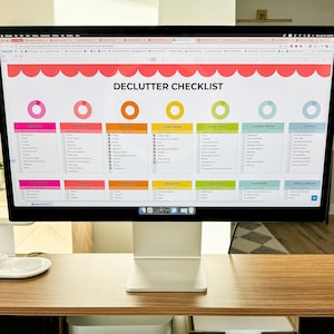 Puede incluir: Una pantalla de ordenador que muestra una lista de verificación de limpieza con una lista de habitaciones y artículos para limpiar. La lista de verificación está organizada en columnas para cada habitación, con un gráfico circular en la parte superior de cada columna. La pantalla está en un escritorio de madera con un teclado blanco.
