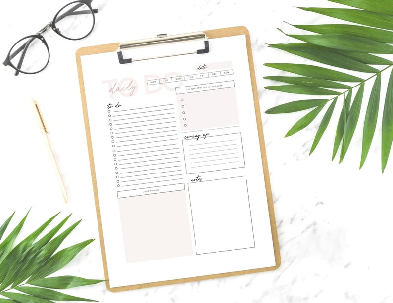 May include: A printable daily to-do list planner with sections for to-do, coming up, and notes. The planner is on a clipboard with a brown background.