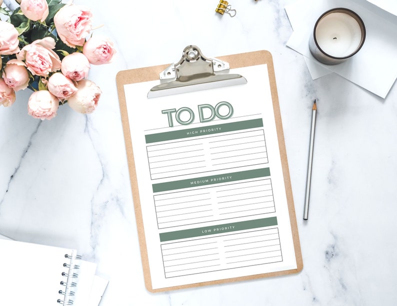 May include: A brown clipboard with a white sheet of paper that has the words "TO DO" written in green at the top. The paper is divided into three sections labelled "High Priority", "Medium Priority", and "Low Priority".