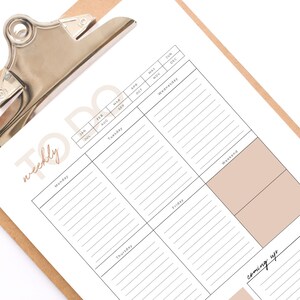 May include: A weekly to-do list planner on a clipboard with a calendar grid for the year. The planner has sections for each day of the week, a weekend section, and a "coming up" section.