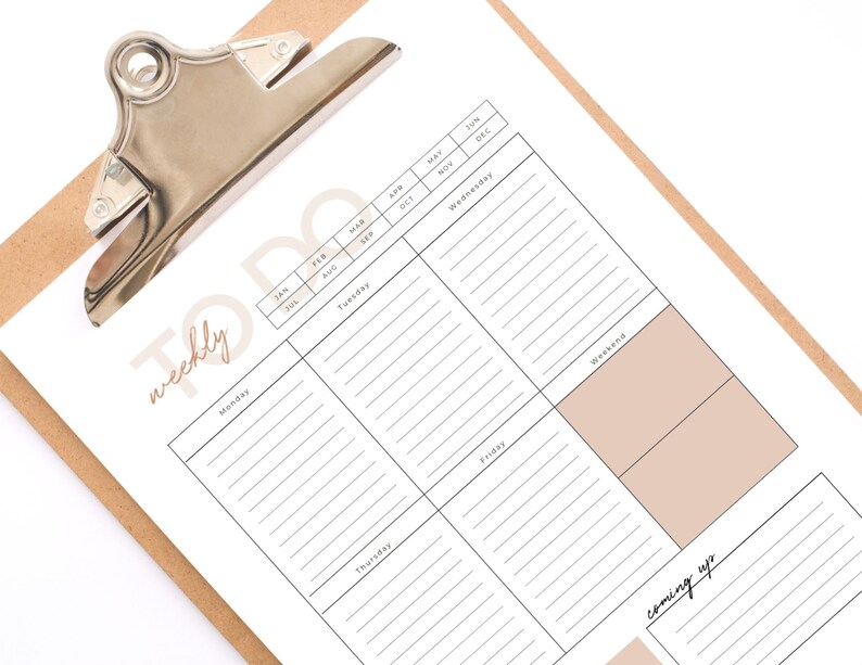 May include: A weekly to-do list planner on a clipboard with a calendar grid for the year. The planner has sections for each day of the week, a weekend section, and a "coming up" section.
