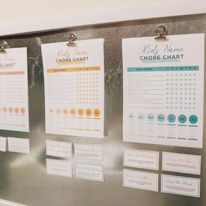 May include: Three printable chore charts with a colorful design and a grid for tracking daily chores. The charts are labeled "Kids Name Chore Chart" and include a list of daily chores and a grid for tracking completion. The charts are displayed on a metal surface with a white frame.