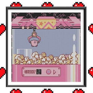 May include: A pixel art style illustration of a pink Kirby character being grabbed by a claw machine. The claw machine is filled with Kirby characters. The machine has a pink and white color scheme and says "CREDIT 8" on the front.