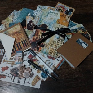 May include: A collection of jazz-themed stationery and supplies. Includes cards, a small notebook, stickers, pens, and wax seals. The cards feature images of musical instruments and jazz musicians. The text "Jazz Night" and "New York Empire State" are visible.