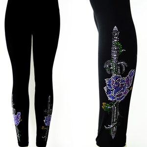 May include: Black leggings with a rhinestone design of a sword and rose on one leg. The design features purple, blue, green, and yellow rhinestones.