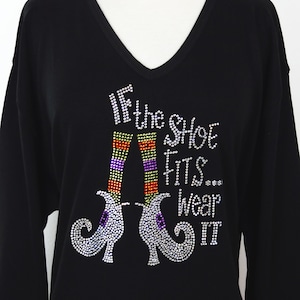May include: Black long-sleeved shirt with a sparkly design of witch's shoes and the text "If the shoe fits... wear it".